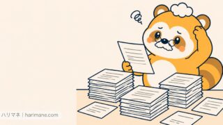 書類の山を前に1枚を手に取り首をかしげるたぬ吉
